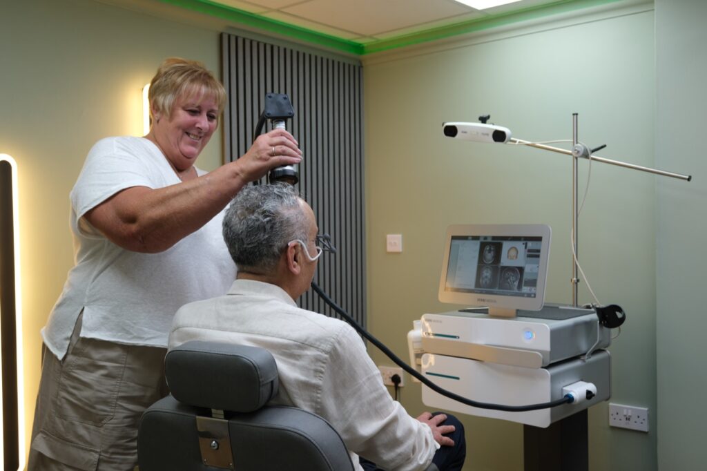 A clinician positioning the stimulation coil for a seated patient