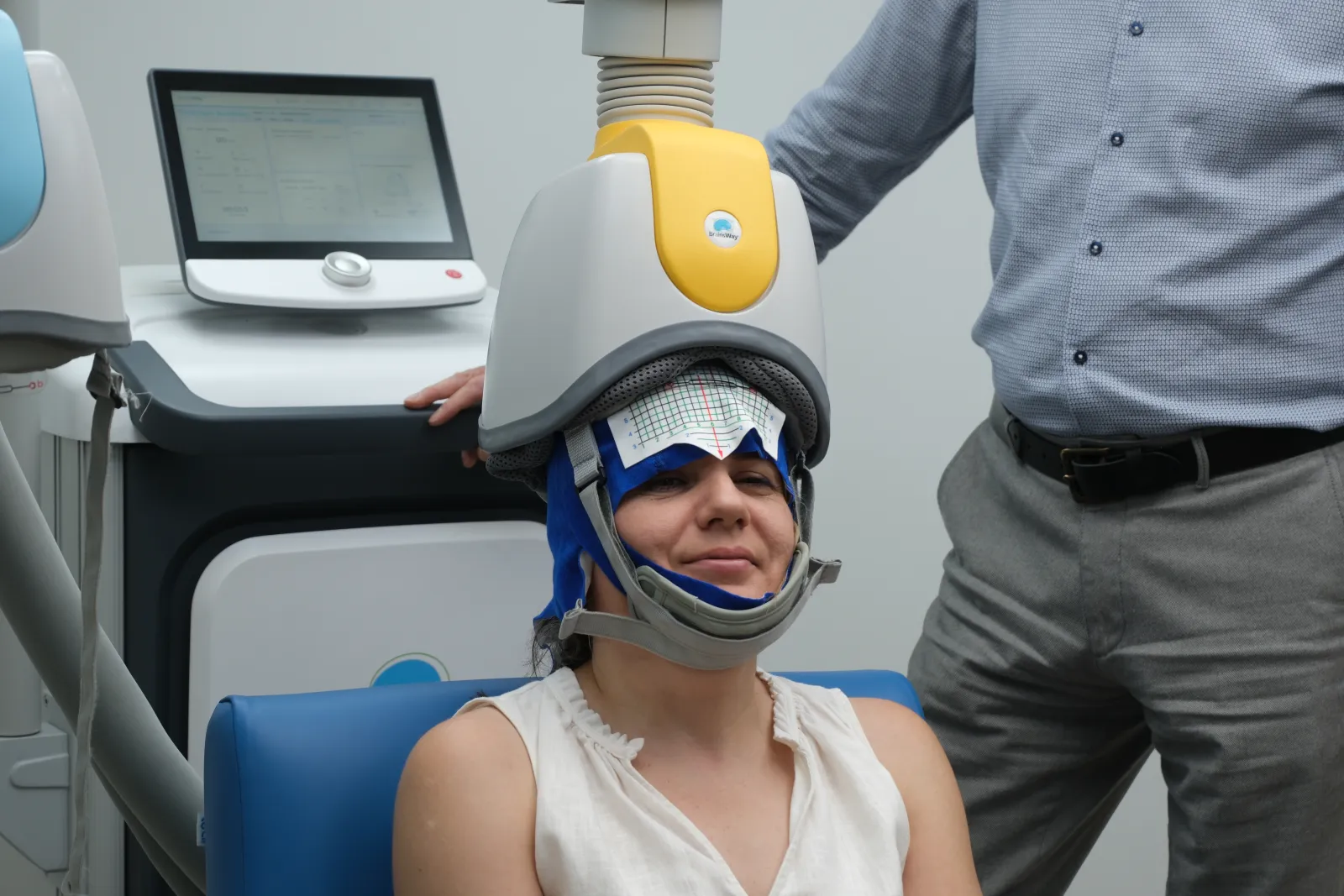 A patient seated wearing the Deep TMS cap and helmet during a session