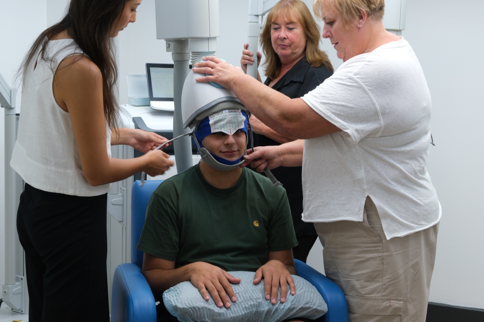 Clinicians fitting a Deep TMS helmet for a patient during a session